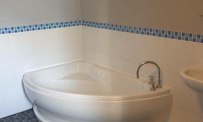 Self catering apartment located on Redford Caravan Park, the bathroom consists of a large corner bath, sink, toilet and enclosed shower.